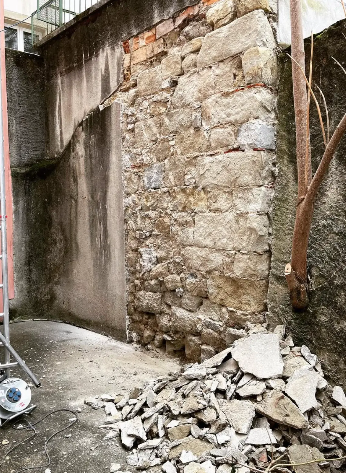 Mur en cours de dégagement, vieux crépi piqué et gravats au sol